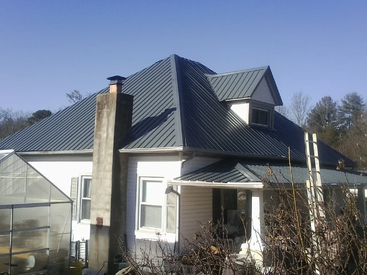 Dark blue standing seam metal roof on a white farmhouse with dormer — Slate & Tile Roof Repair by Roofing Brothers in Obernburg