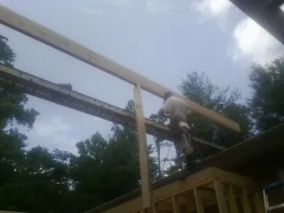 Carpenter setting a ridge beam over a new addition frame — Ice Dam Removal by Roofing Brothers in Obernburg