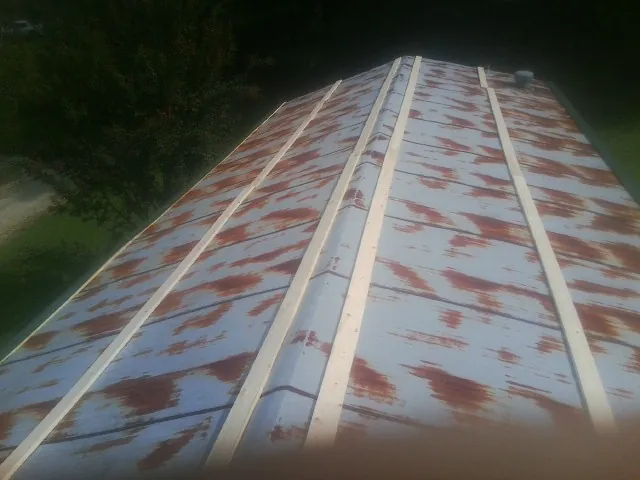 Rusted metal roof panels with new wood purlins before replacement — Storm Damage Roof Repair in Obernburg by Roofing Brothers