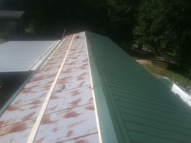Old rusted panels beside newly installed green metal roofing — Wind Damage Roof Repair by Roofing Brothers in Obernburg