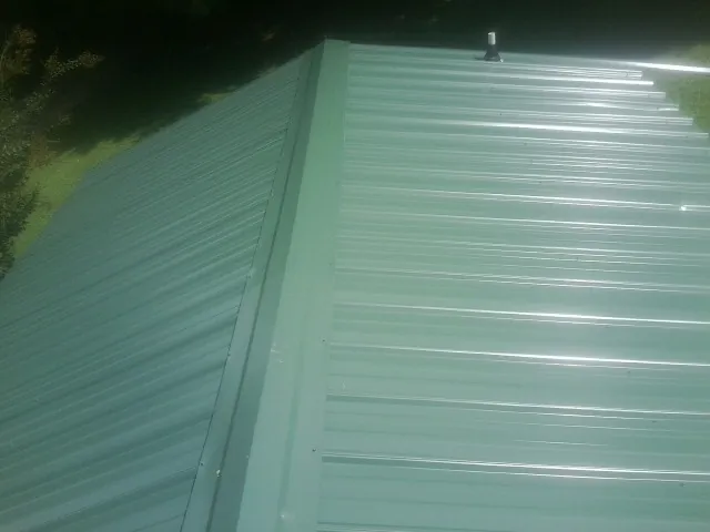 New green metal panels meeting at the ridge of a roof — Flat Roof Repair work by our crew in Obernburg