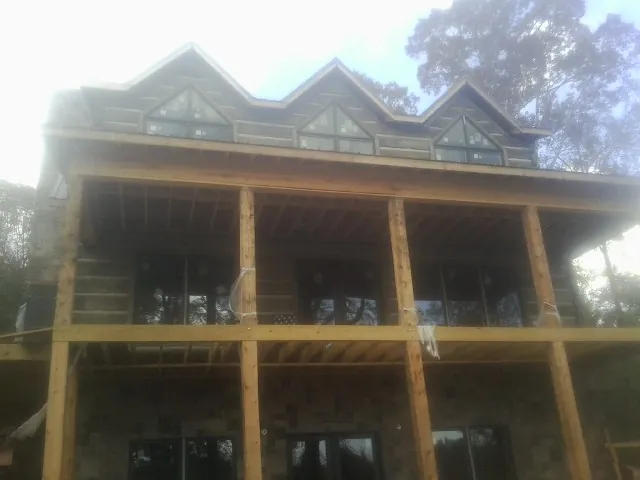 Dormers and porch framing on a large log home under construction — Roof Coating work by our crew in Obernburg
