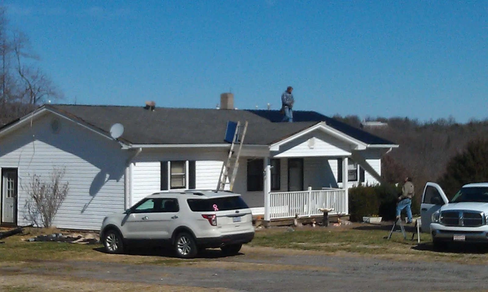 Roofers stripping shingles from a white ranch house roof in Obernburg