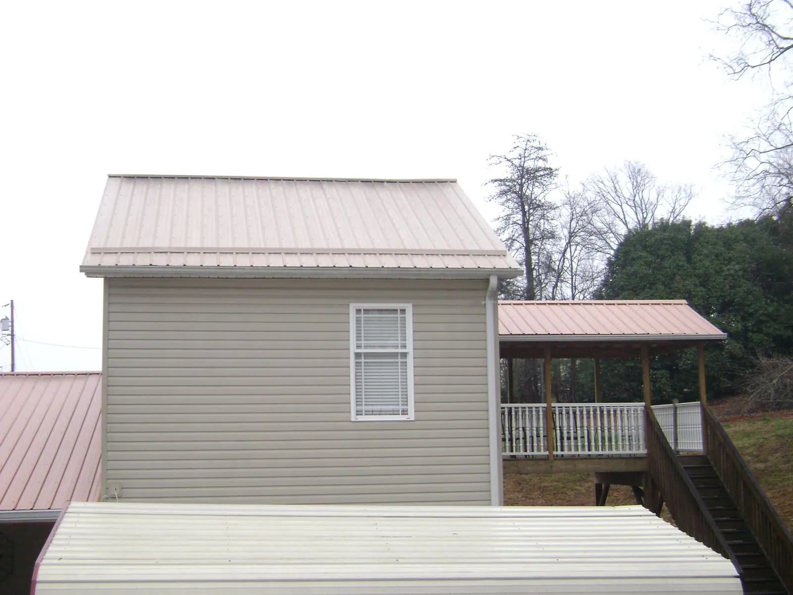 Tan metal roofs on a two story addition and attached porch, from a Roof Replacement job in Obernburg