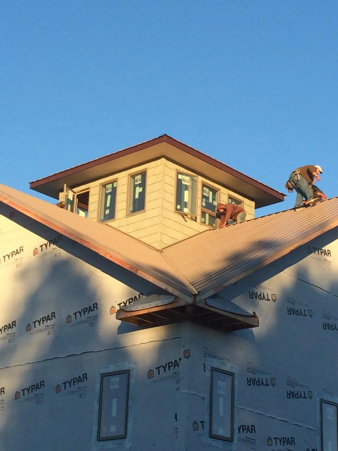 Roofers working around a rooftop cupola on a new metal roof at sunset — Roof Waterproofing in Obernburg by Roofing Brothers